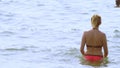 Blond girl in a bathing suit and black sunglasses. woman in a red swimsuit walks into the sea Royalty Free Stock Photo