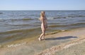 Blond girl in a bikini on the beach. Beautiful young woman in a colorful bikini on sea background Royalty Free Stock Photo