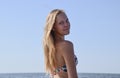 Blond girl in a bikini on the beach. Beautiful young woman in a colorful bikini on sea background Royalty Free Stock Photo