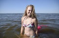 Blond girl in a bikini standing in the sea water. Beautiful young woman in a colorful bikini on sea background. Royalty Free Stock Photo