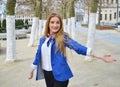 Happy blond young woman in the park with enigmatic smiling