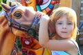 Blond girl with fairground horse enjoy in park