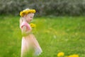 Blond girl in field of yellow dandelions. Summer day. Little lady in pink dress holds flowers. Selective focus Royalty Free Stock Photo