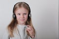 Blond girl with headphones listening music and singing. Cute little girl making a rock-n-roll sign. Royalty Free Stock Photo
