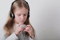 Blond girl with headphones listening music and singing. Cute little girl making a rock-n-roll sign. Royalty Free Stock Photo