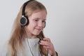 Blond girl with headphones listening music and singing. Cute little girl making a rock-n-roll sign. Royalty Free Stock Photo