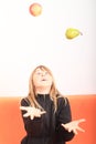 Blond girl juggling with apple and pear