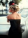 Blond girl model with bright makeup and curly hairstyle in retro style posing near old white car Royalty Free Stock Photo