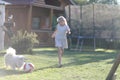 Blond girl playing with a ball and a little furry dog