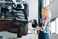 Blond girl screwing car wheel at the garage