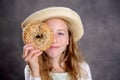 Blond girl with straw hat looking through a big bagel Royalty Free Stock Photo