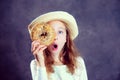 Blond girl with straw hat looking through a big bagel Royalty Free Stock Photo