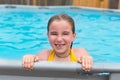 Blond girl swimming in the pool with red cheeks