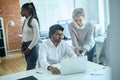 Blond girl teaching Hindoo colleague working with laptop Royalty Free Stock Photo