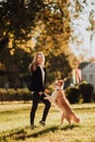 Blond girl train her dog border collie in green park in sunshine