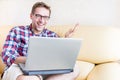 Blond guy is sitting on the sofa and laughing about funny content on social media