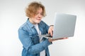 Blond guy is typing on a keyboard a message on a laptop on a white background