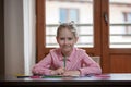 Blond hair school girl, sitting at the desk with colored pencils in her hand, smiling Royalty Free Stock Photo