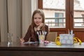 Blond hair school girl, sitting at the desk with school supplies, smiling Royalty Free Stock Photo