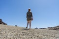 Blond hair teen in relaxing mood at remote lunar, volcanic and arid desert. Back of Spiritual woman in green dress walking alone Royalty Free Stock Photo