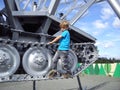A blond-haired boy in a blue T-shirt climbed onto a metal structure. An old tractor with caterpillar wheels turned into a mosquito Royalty Free Stock Photo
