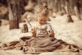 Blond haired girl in cozy knit earth toned clothes playing with feather and showing true emotions Royalty Free Stock Photo