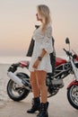 Blond haired woman and modern custom bike on beach