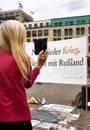 Blond haired woman takes cell phone photo of a sign against war at a demonstration in Berlin Germany Royalty Free Stock Photo