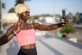 Blond haired young black fitness woman waving hand while having video call on her smart phone during outdoor walk. Royalty Free Stock Photo