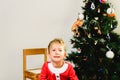Blond and handsome 5 year old boy dressed up as santa claus next to christmas tree and white background with space for text Royalty Free Stock Photo