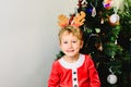 Blond and handsome 5 year old boy dressed up as santa claus next to christmas tree and white background with space for text Royalty Free Stock Photo