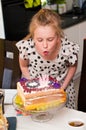 Blond happy young girl blowing candles on her birthday cake Royalty Free Stock Photo