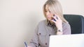 blond independent woman at office. Portrait of successful modern businesswoman speaking by phone and making notes while Royalty Free Stock Photo