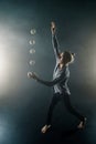 Blond juggler with white balls on black background