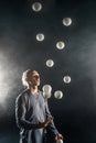 Blond juggler with white balls on black background