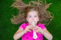 Blond kid children girl playing flute lying on grass Royalty Free Stock Photo