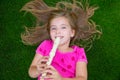 Blond kid children girl playing flute lying on grass