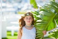 Blond kid girl at banana tree leaves in bright day Royalty Free Stock Photo