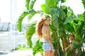 Blond kid girl at banana tree leaves in bright day Royalty Free Stock Photo