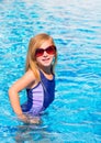 Blond kid girl in blue pool posing with sunglasses Royalty Free Stock Photo
