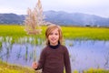 Blond kid girl outdoor holding spike in wetlands lake Royalty Free Stock Photo