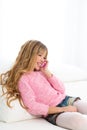 Blond kid girl playing fun talking to mobile phone on sofa