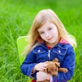 Blond kid girl with puppy pet dog in green grass Royalty Free Stock Photo