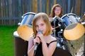 Blond kid girl singing in tha backyard with drums Royalty Free Stock Photo