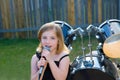 Blond kid girl singing in tha backyard with drums Royalty Free Stock Photo