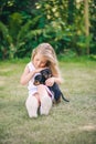 Blond kid girl in white dress petting a puppy dog outdoors Royalty Free Stock Photo