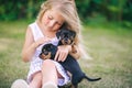 Blond kid girl petting a puppy dog in green grass Royalty Free Stock Photo