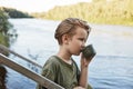 Blond little boy drinking hot coffee or tea from thermos isolated over nature landscape, male child spending time in open air, guy Royalty Free Stock Photo