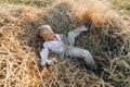 Blond little boy having fun jumping on hay in field. summer, sunny weather, farming. happy childhood. countryside Royalty Free Stock Photo