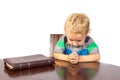 Blond little boy praying to God after reading the bible Royalty Free Stock Photo